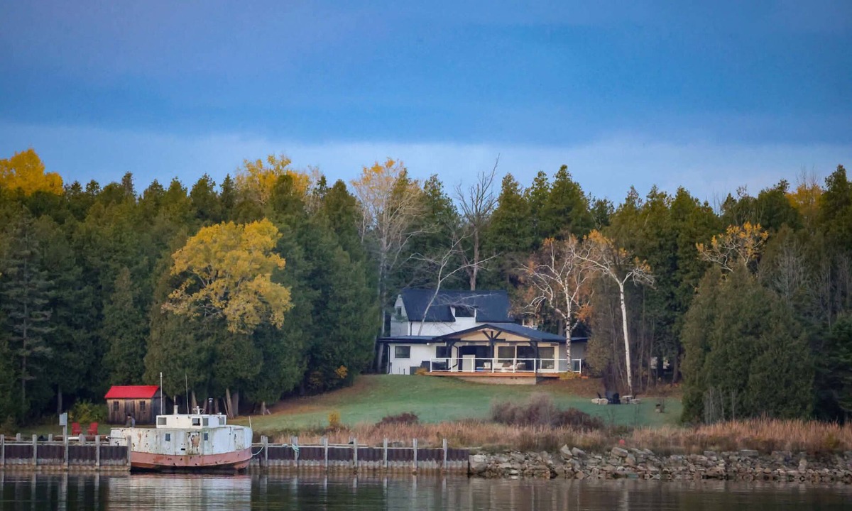 Stokes Bay House | Midnight Star is a bright, modern Stokes Bay waterfront cottage with 3 bedrooms, 2 bathrooms, a private dock, sauna, hot tub, stone fireplace, open-concept living, and epic sunsets—perfect for easy Bruce Peninsula lake days.