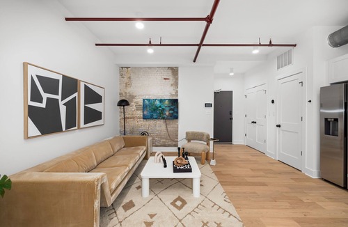 Old Town Alexandria Apartment | Design-forward flat in Old Town's most iconic building. Exposed brick, bold red ceiling pipes, corner bedroom bathed in natural light. Modern kitchen, quiet side street. Steps from 100+ restaurants & waterfront. A LovableBNB Collection listing.