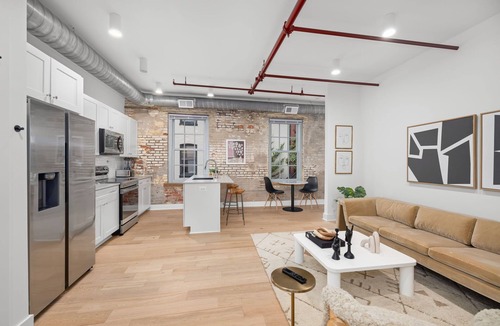 Old Town Alexandria Apartment | Design-forward flat in Old Town's most iconic building. Exposed brick, bold red ceiling pipes, corner bedroom bathed in natural light. Modern kitchen, quiet side street. Steps from 100+ restaurants & waterfront. A LovableBNB Collection listing.