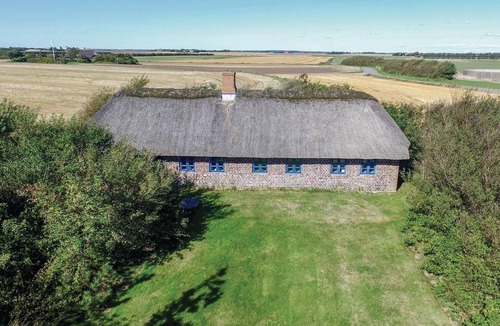 Tim House | In the countryside and surrounded by fields lies this idyllic farmhouse with a thatched roof.