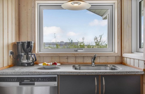 Havnsø House | The cottage has an inviting kitchen-living room with a fireplace and a partially covered terrace.