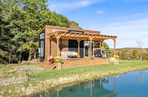 Brackney Cabin | Waterfront Tiny House Perched on the Pond Covered Deck at Water’s Edge