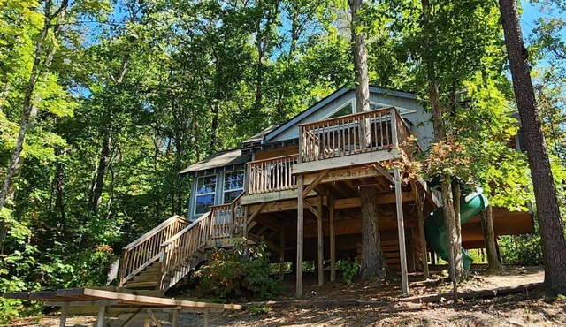 2-story treehouse with a cargo net connecting the upstairs lofts, a large balcony with a slide to the ground level, sleeps 10.