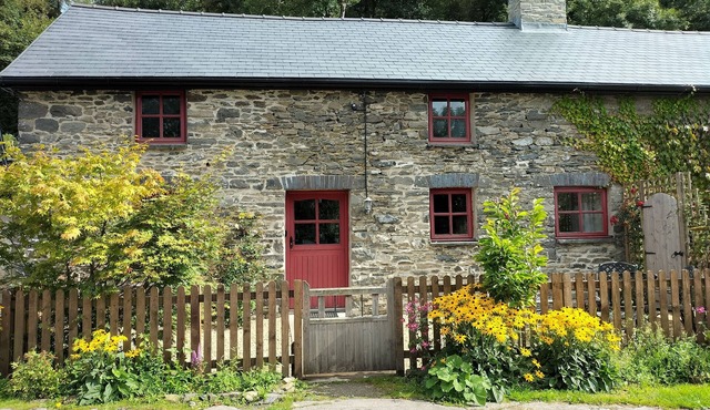 A cosy former horse stable with stone walls and old beams throughout