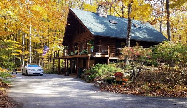 Beautiful log home with wrap-around deck surrounded by trees.