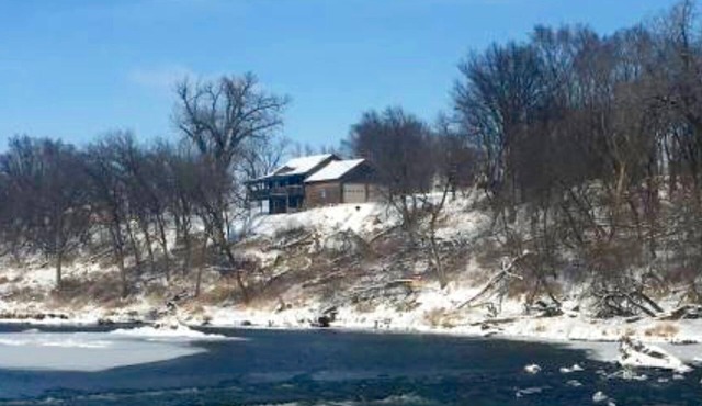 Cabin on bluff of Big Sioux River with rushing waters of the Klondike Dam below.