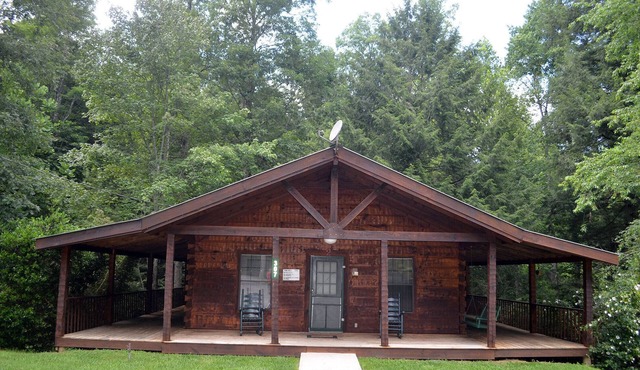 cozy cabin in the woods in a relaxing area with wrap around porch rocking chairs