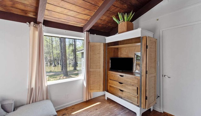 Emerald Cottage offers a laid-back stay surrounded by towering trees, with a spacious deck, kayaks and canoes to paddle through the cypress forest, and a firepit perfect for slow evenings outside.