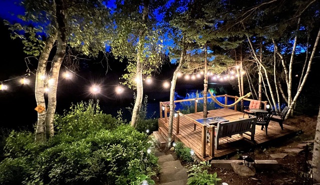 Luxurious rustic wooden chalet on edge of tranquil pond in nature next to beach.