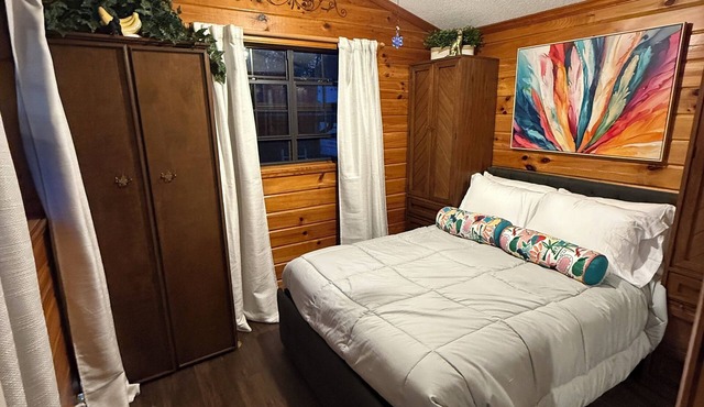 MTM Premier Funky Jungle sleeps 4 in a charming log cabin with serene lakefront views. Rustic yet comfortable, ideal for small families or groups, with access to campground amenities and seasonal activities.