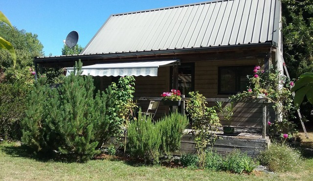 Small detached wooden house in well-maintained fenced park.