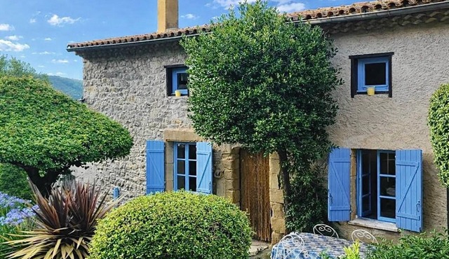 Stone house with character, nestled in a verdant setting.