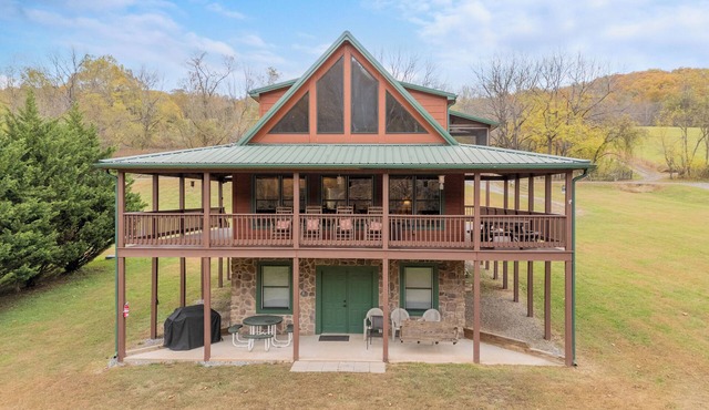 Sunny riverside cabin with loft views, big deck, game room, porches, and open lawn.