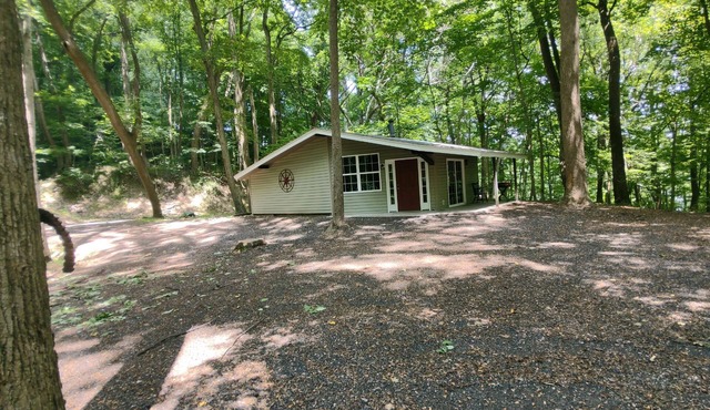 The Chalet is located in the woods of a gated property with a covered porch.