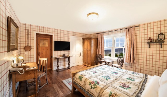 The wooden floors, vintage furniture, and tartan accents create a comfy room
