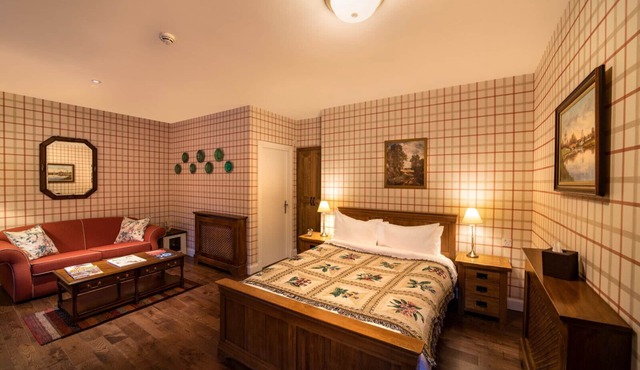 The wooden floors, vintage furniture, and tartan accents create a comfy room