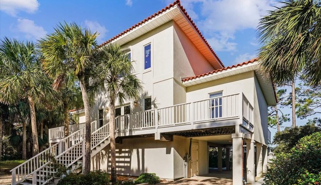 THIS BEAUTIFULLY FURNISHED HOME is bay front on one picturesque acre of pines and palms.