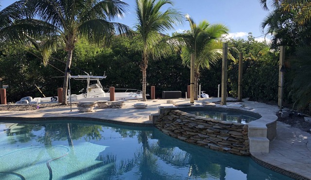 Tropical waterfront oasis with private dock, pool, waterfall spa, tiki huts.