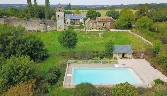 Two houses with a large swimming pool next to the ruins of a medieval castle
