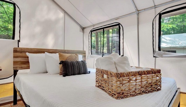 Unplug in comfort—glamping tent with real beds, electricity, fire ring, bathhouse, and nearby pond.