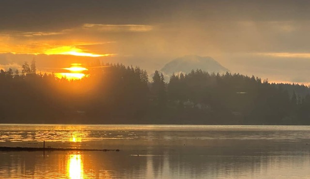 Family-friendly waterfront home with sunrise views of Mt. Rainier. Enjoy zero-bank access, kayaks, bocce ball, a cozy fire pit, and hot tub. Plenty of space with 2 kings, queen + trundle, and queen Murphy bed. A Perfect PNW escape minutes from Allyn.